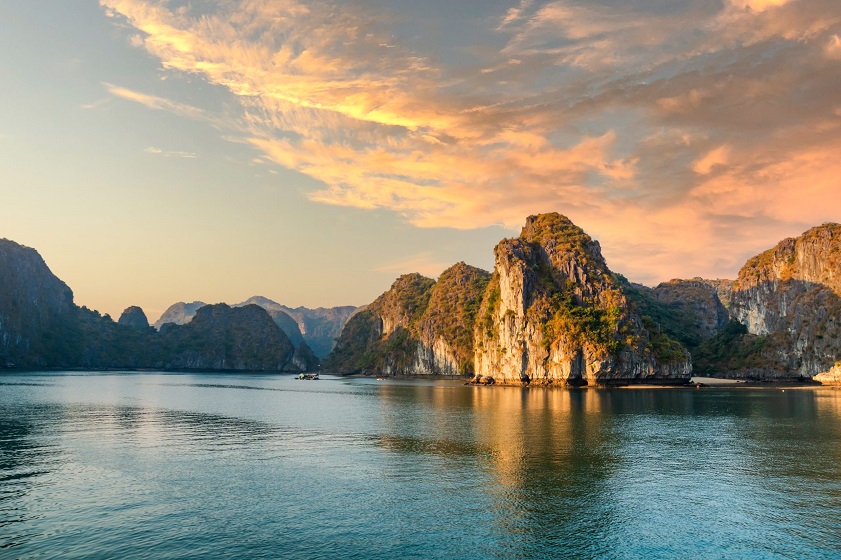 Ha Long Bay’s limestone islands shimmer under the golden sunrise
